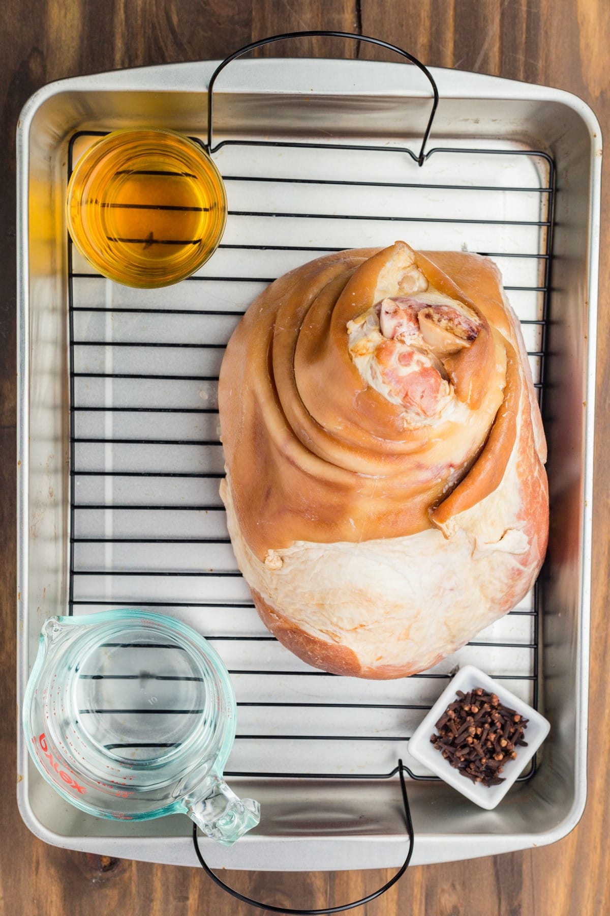 Learn How to Cook a Ham with this informative post, plus an amazing glaze to keep the ham moist and delicious. Ham, water, juice and cloves in a roasting pan.