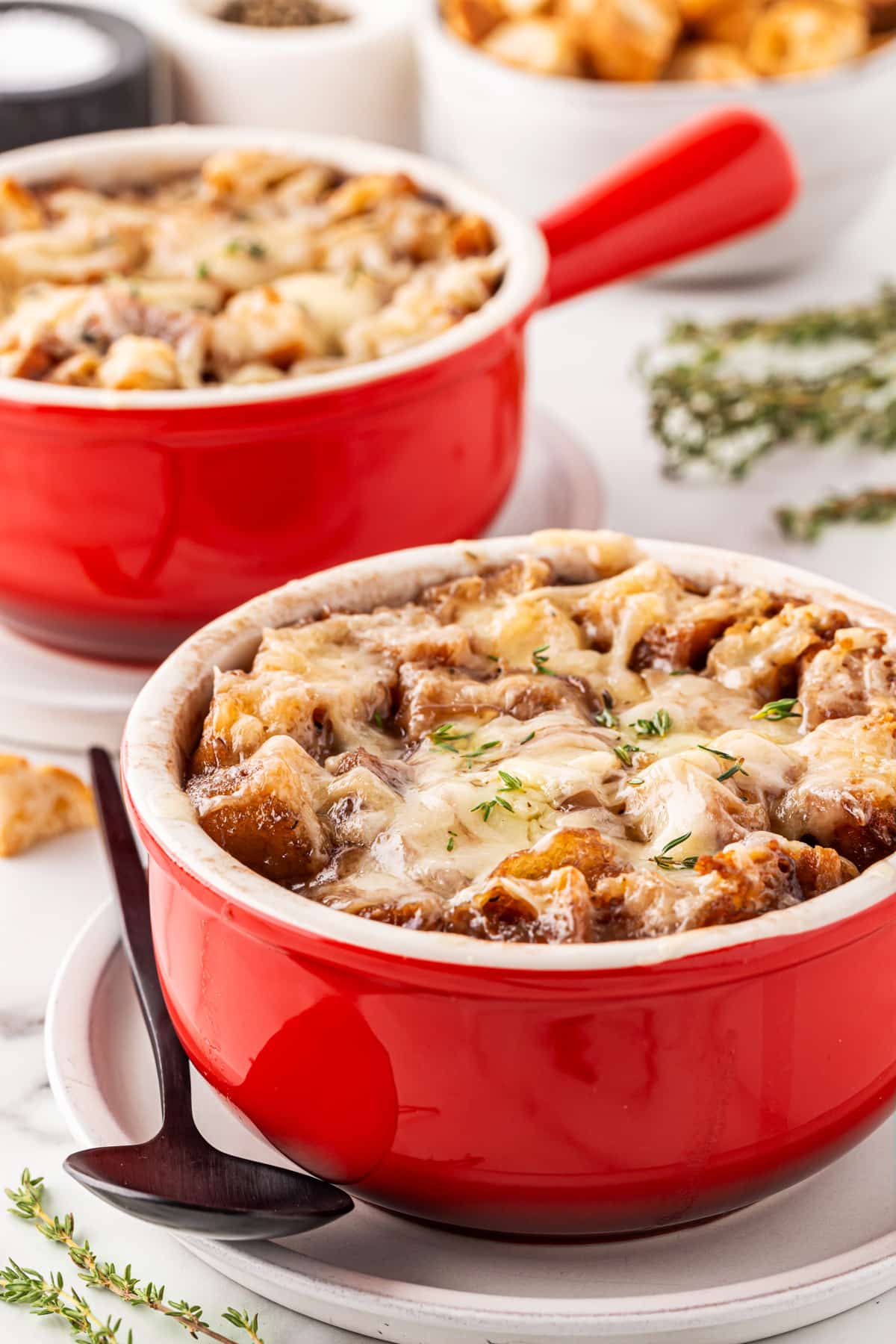 This French Onion Soup for Two is the perfect meal for a cold night in February for Valentine's Day or any night for that matter. Front view of French Onion Soup for Two in red bowls with handles.