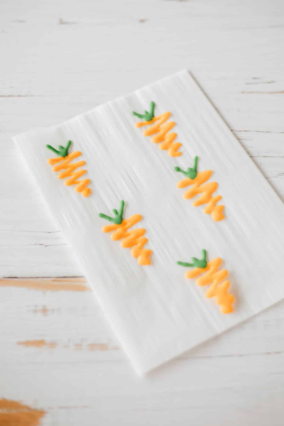 These Carrot Cake Cookies couldn't be easier with a mix and canned icing. All you need to do is a little candy carrot, and you have the most adorable cookie around. Candy carrot on parchment.