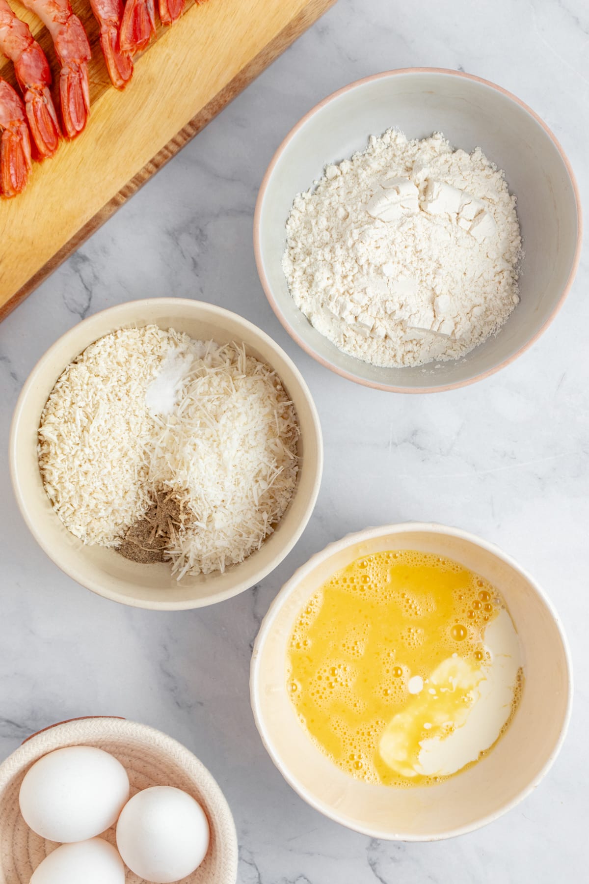 This Coconut Shrimp Recipe makes an amazing appetizer, but with rice and a salad, it can be a main dish also. Three bowls with breading ingredients.